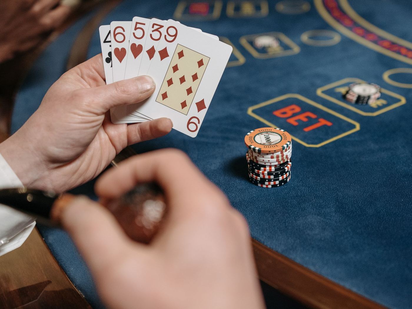 Karty w dłoni gracza i żetony na stole pokerowym